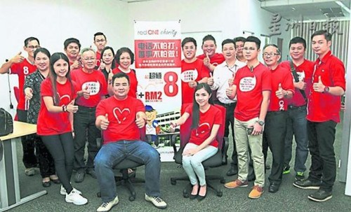 redONE销售总监郑明傅（坐者左），率领一支年轻的团队为芙蓉7所华小推出爱心华教配套。（马来西亚《星洲日报》）