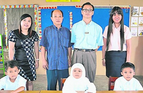 新邦木阁华小3名新生与邱峋华（右二起）、吴始发、级任教师赖莉芳合照；右一为郑玉妹。（马来西亚《星洲日报》）