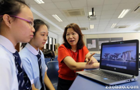 义安中学华文教师张露（右）指导两名高级华文学生，如何在限时两分钟内针对视频内容发表意见。（新加坡《联合早报》；谢智扬/摄）