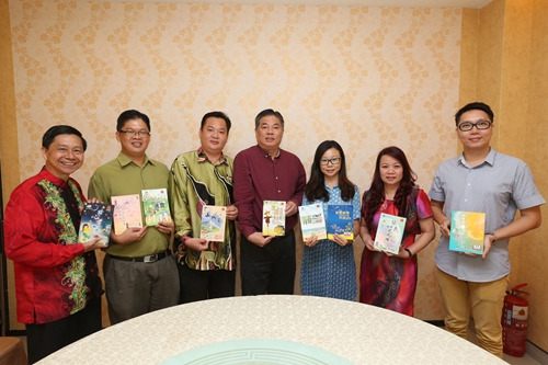 周锦聪（左二）与出版社负责人、教育部官员、督学团及评委老师们，拿着历届出版的“全国中学生文学创作比赛”得奖文学作品集合影留念。（马来西亚《星洲日报》）