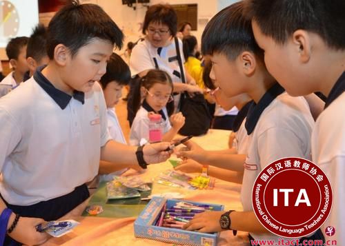 中国侨网光道小学举办的“小小店屋”比赛中，学生以母语“推销”摊位物品，让其他学生用游戏钞票购买，从而鼓励他们实用母语，也灌输基本的创业知识。（新加坡《联合早报》/光道小学提供）